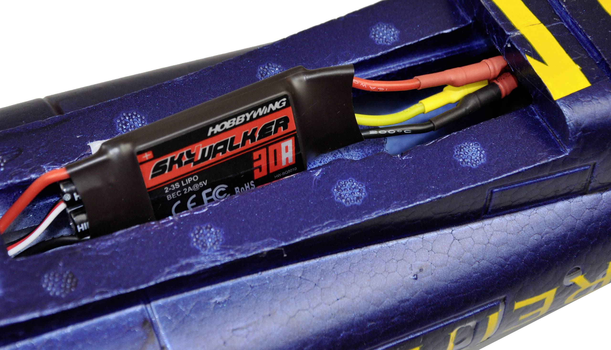 An electric motor controller in a model aircraft displays the inscription 'SKYWALKER 30A'. Cables are connected to it.