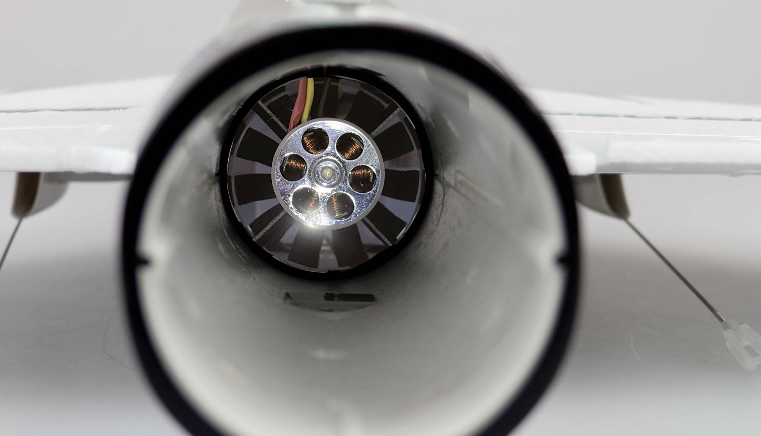Close-up of a model aircraft engine from behind, with visible turbine blades and wires.