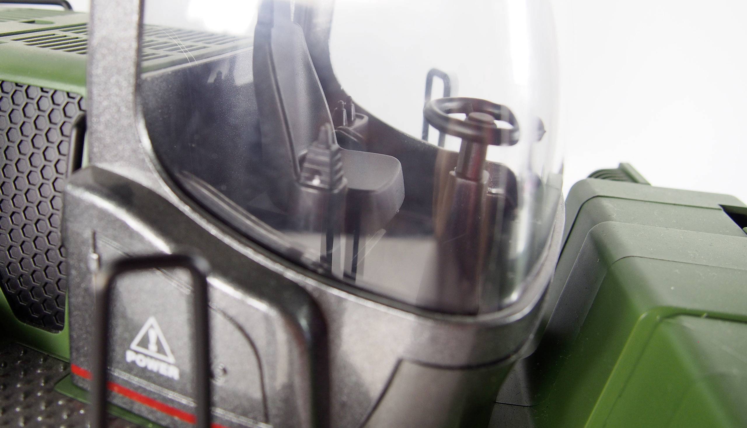 Close-up of a vehicle with a highly magnified view of the cabin, showing a driver's seat and a steering wheel.
