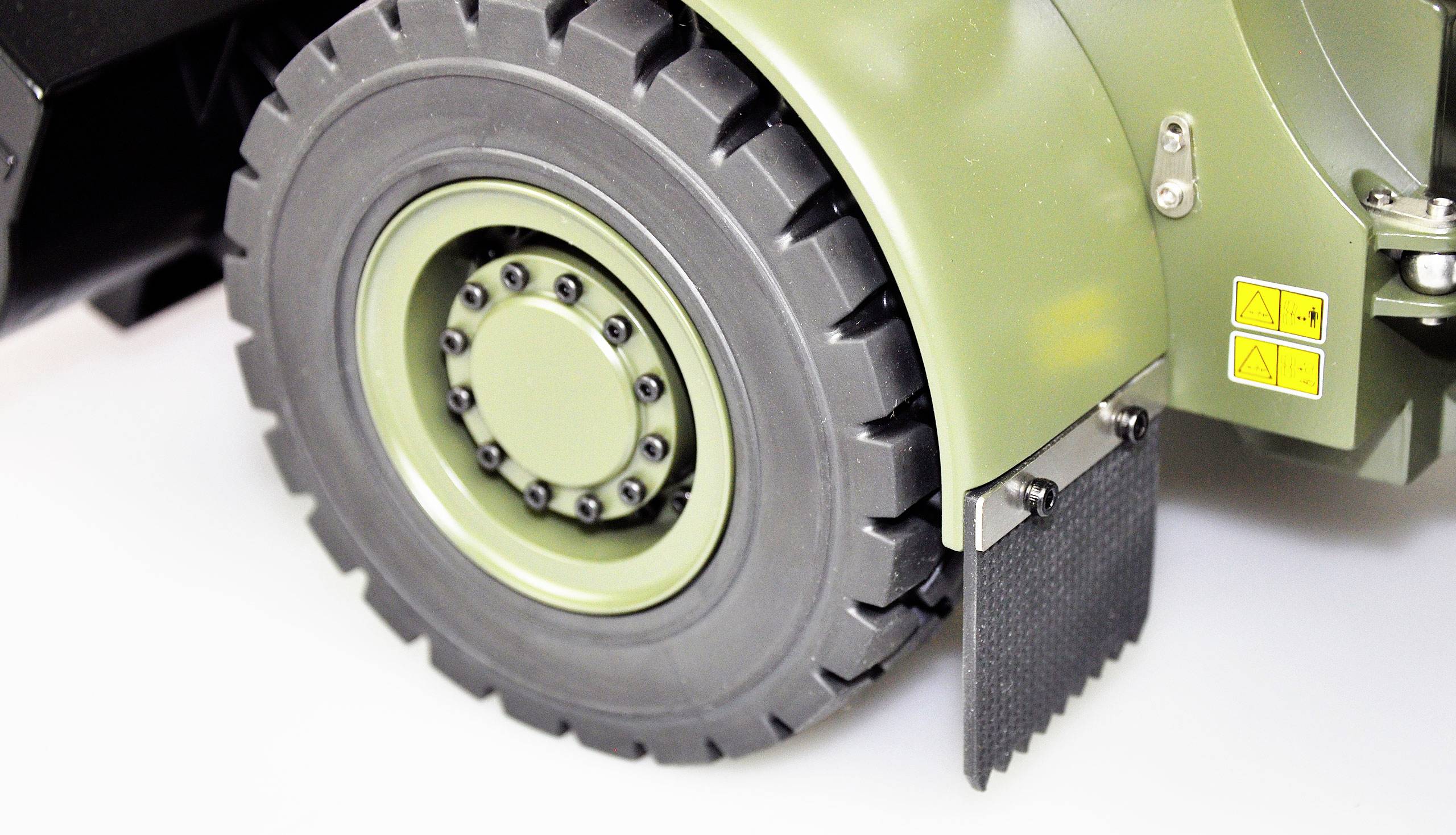 Close-up of a large green vehicle wheel with detailed tread and mudguard. Suitable for off-road components or military vehicles.