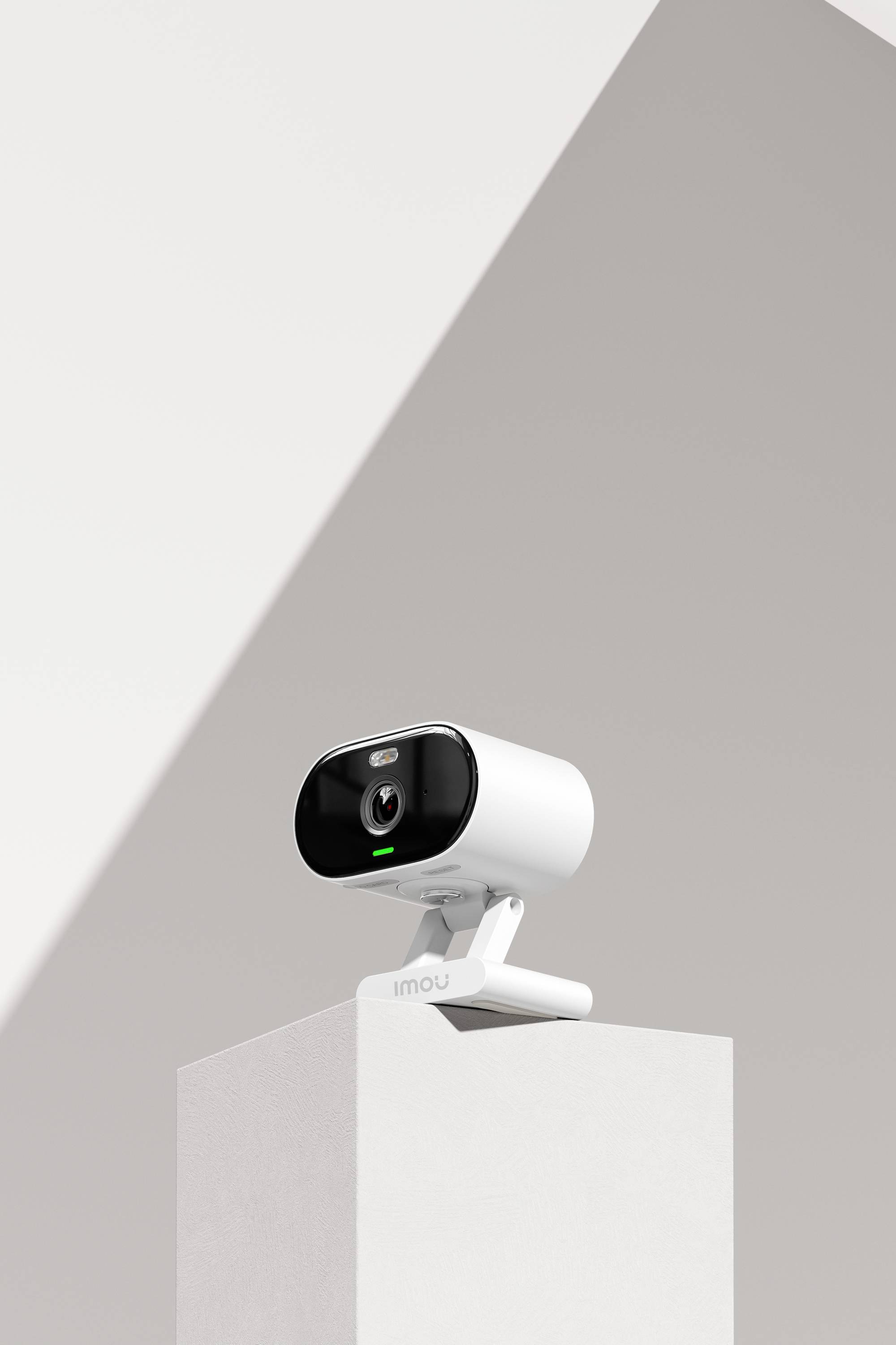 A white surveillance camera stands on a plinth against a minimalist background.