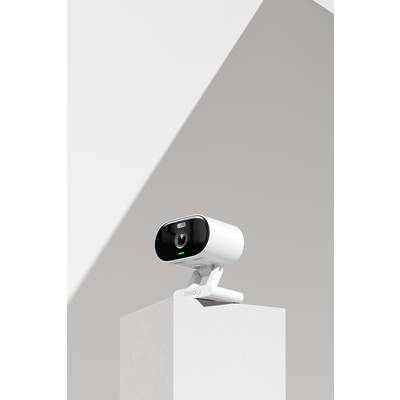 A white surveillance camera stands on a plinth against a minimalist background.