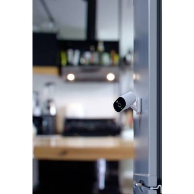 Security camera mounted on a fridge, showing the interior of a modern kitchen with blurred appliances in the background.