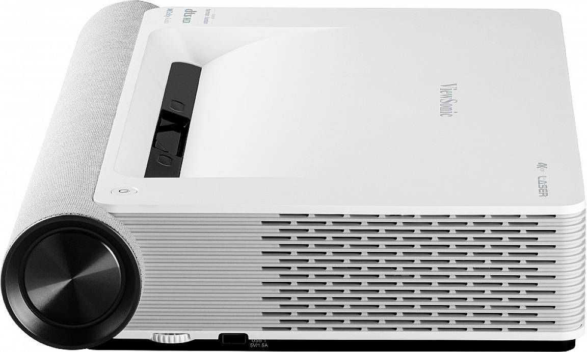 A white projector with ventilation slots on the side, a black control panel on top, and a large focus wheel at the front.