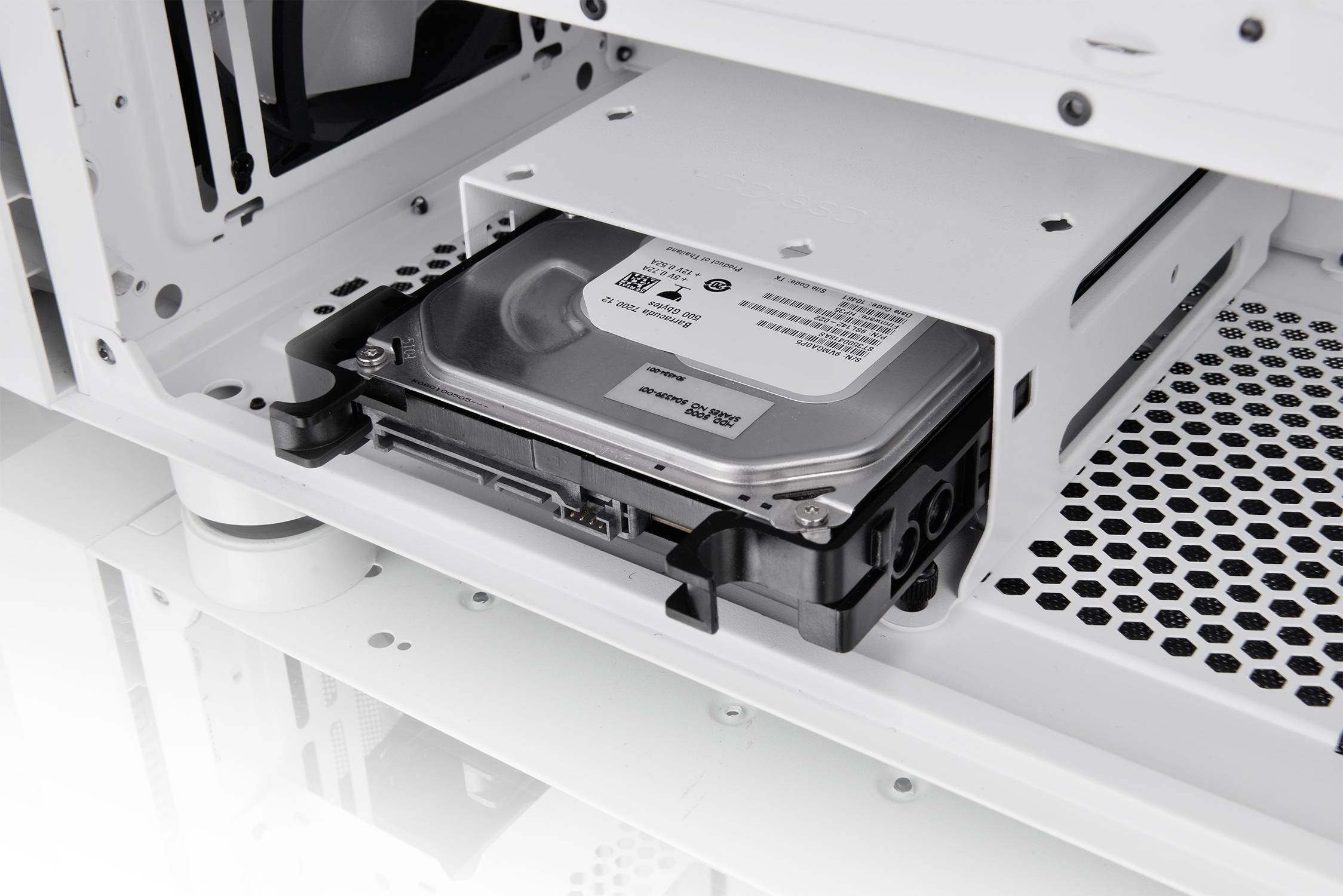 A hard drive is installed in an open white computer case, allowing a view of the internal hardware.