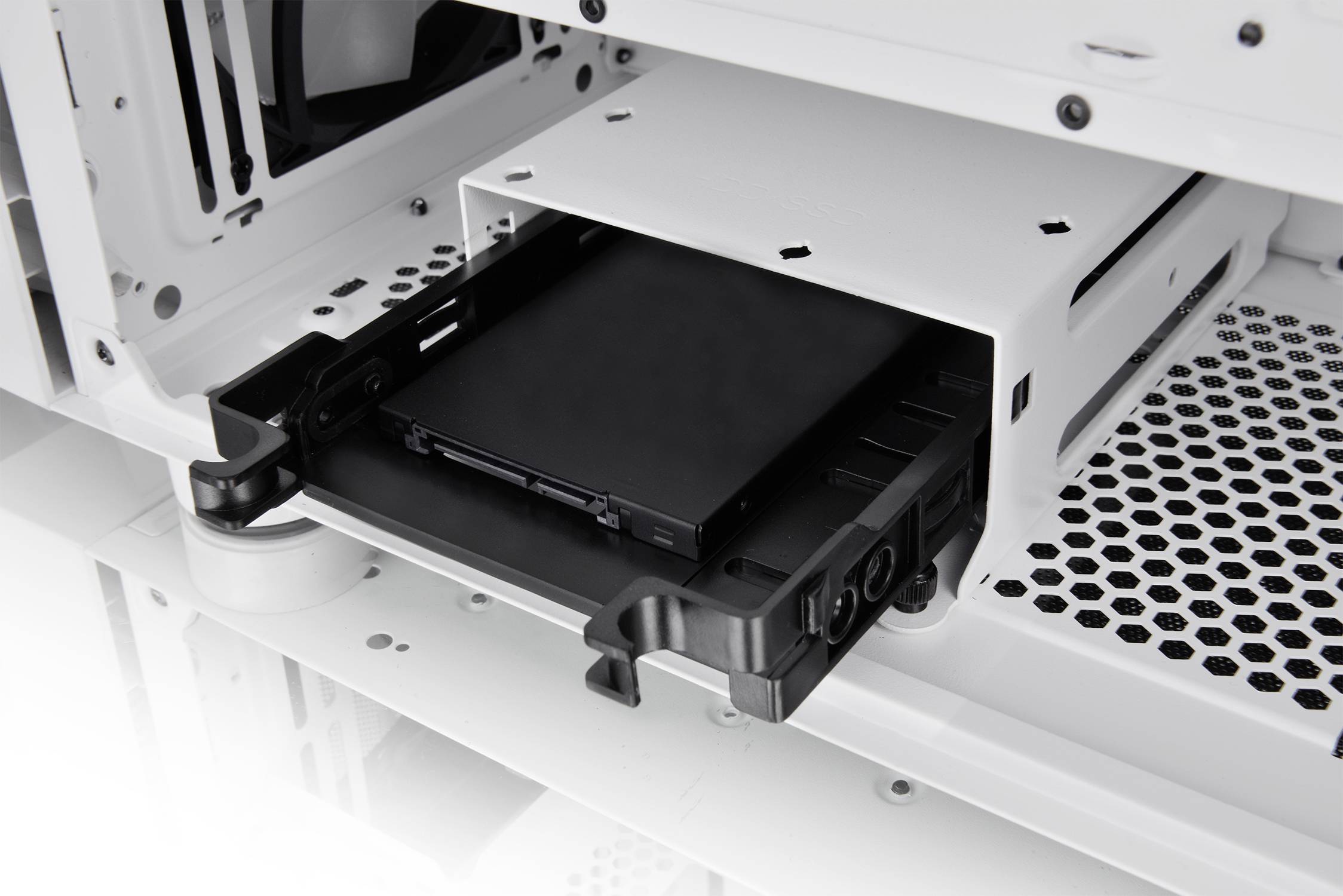 Black hard drive is being inserted into a white computer case. The view shows the insertion mechanism and interior of the case.