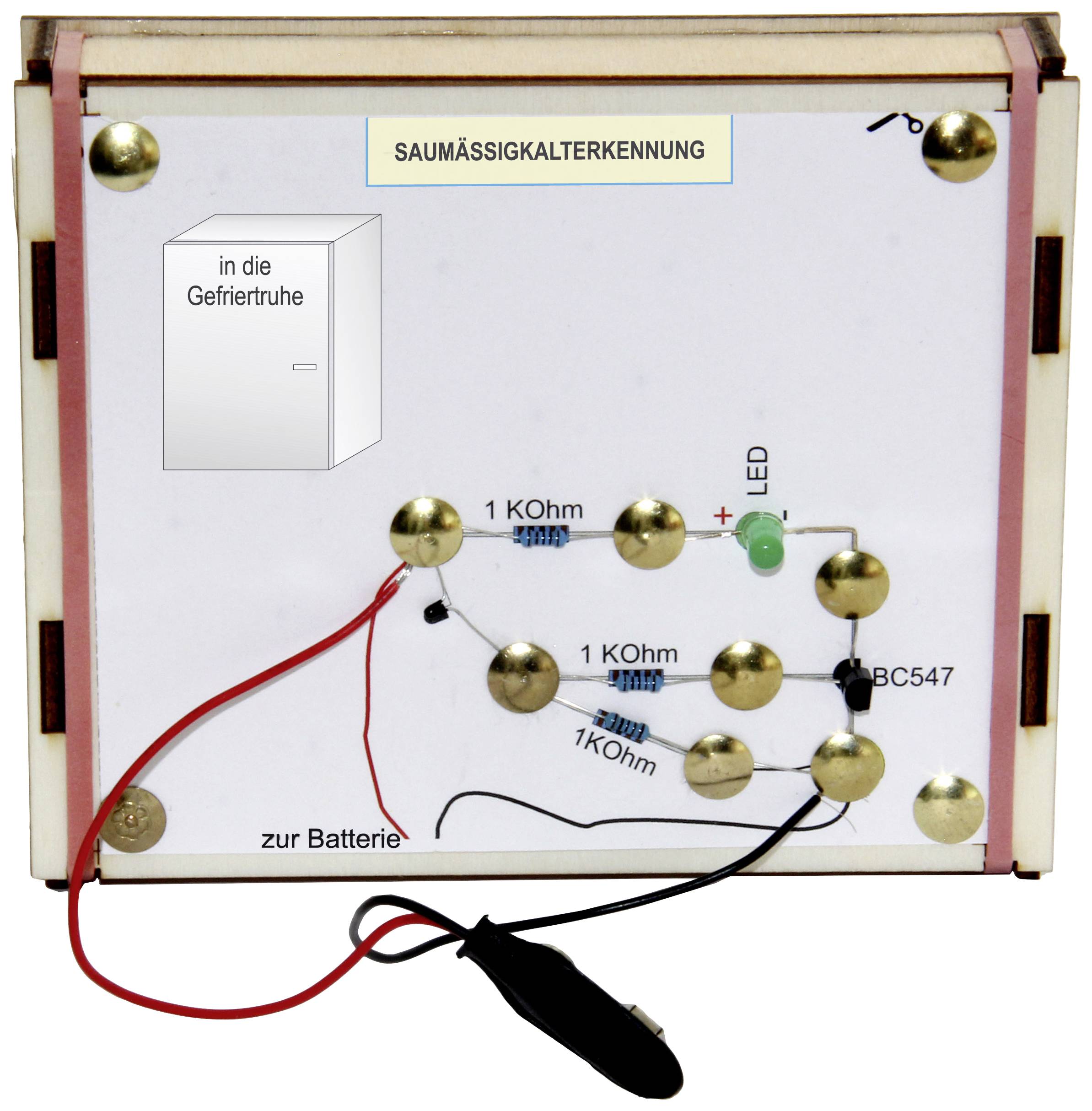A circuit on a white board with various resistors, wires, and an LED light. Labelled 'into the freezer' and 'to the battery'.