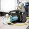 A blue and white vacuum pump with a yellow hose in front of an air conditioning connection. The brand is 'Makita'.
