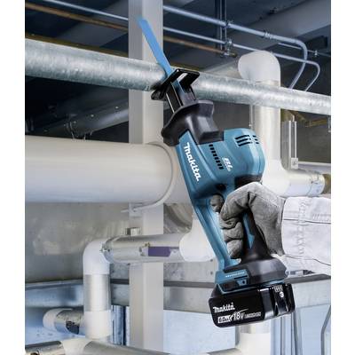 A person is using a blue cordless reciprocating saw to cut a metal pipe. The background shows industrial pipework.