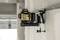A laser level is attached to a building. It projects a green laser line onto the wall to mark the height.