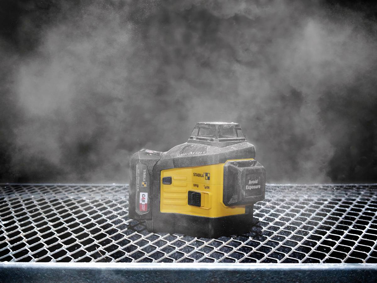 A yellow and black laser device sits on a metal grid in a steamy environment.