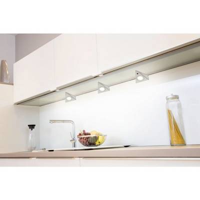 Modern kitchen with white worktops and cabinets. Three triangular pendant lights illuminate the area. Fruit bowl and glass container to the left.
