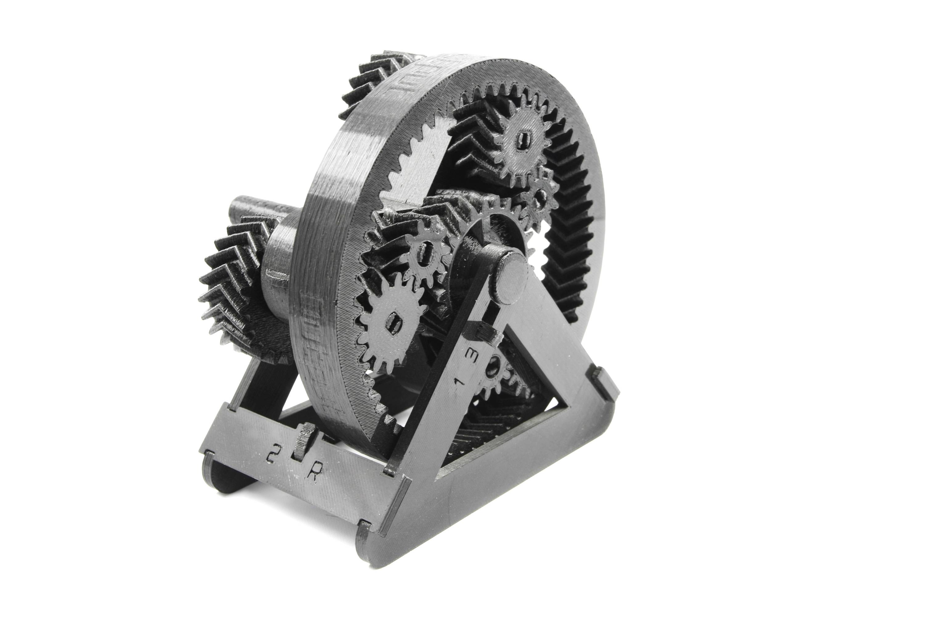 A complex gear model displays several interlocking gears on a triangular stand, demonstrating mechanical processes.