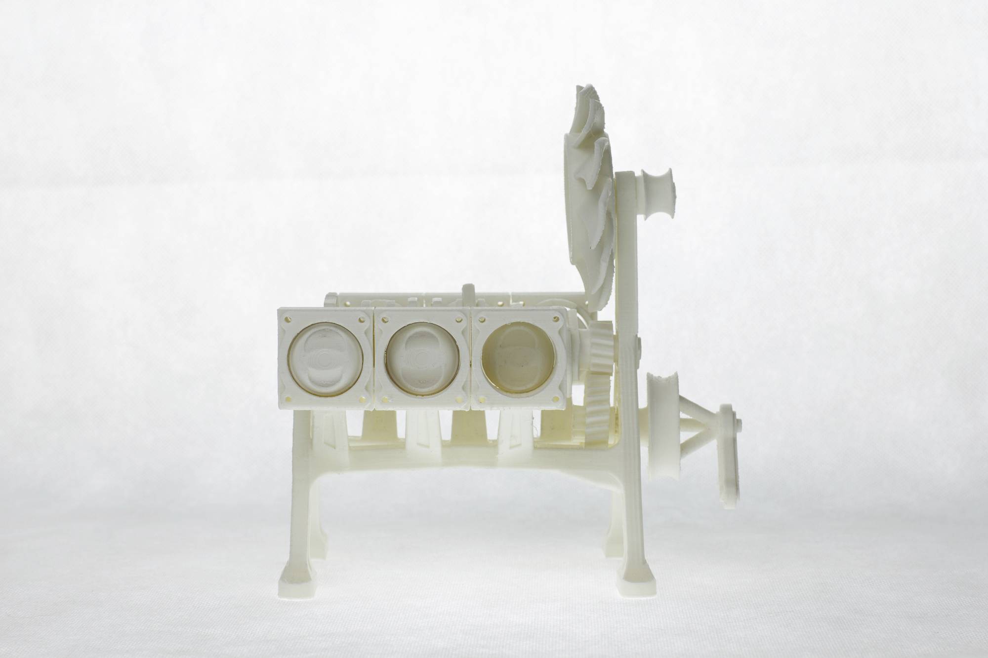 A white 3D model of an engine, shown from the side, with visible cylinders and fan wheels on a neutral background.