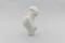 A white, abstract sculpture with a smooth, organic form. It stands upright against a neutral background.