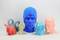 Colourful 3D-printed figures: a blue head with a cap, a pink head, a red hare, a beige figure, a laughing blue cat, and two blue rings.