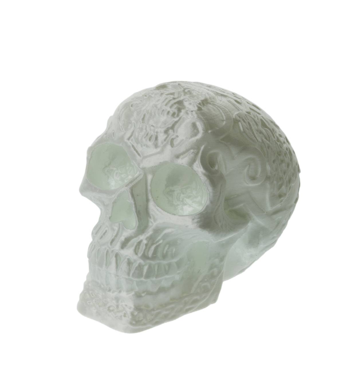A translucent glass skull with engraved patterns and empty eye sockets, depicted on a white background.