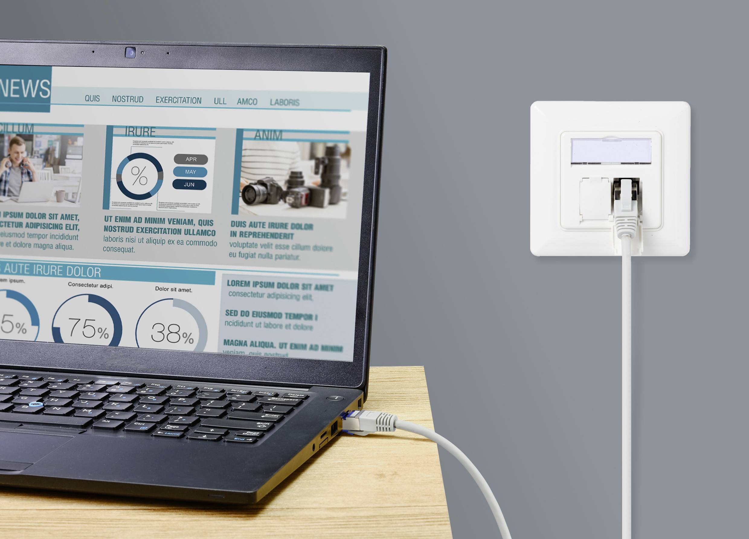 A laptop on a table is connected to a network socket via an Ethernet cable. Messages and diagrams are displayed on the screen.