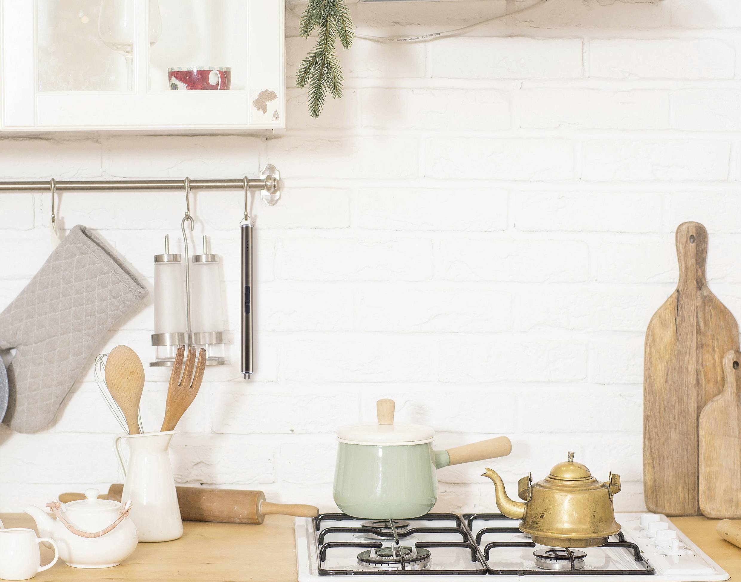 Kitchen with cooker, saucepan and kettle. Wooden boards and kitchen utensils on the wall. Bright and cosy atmosphere.