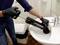 A person wearing gloves is using a plunger to unblock a sink.