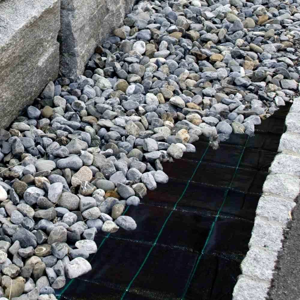A drainage sump filled with gravel, surrounded by stone slabs for stabilisation. It serves to drain rainwater.