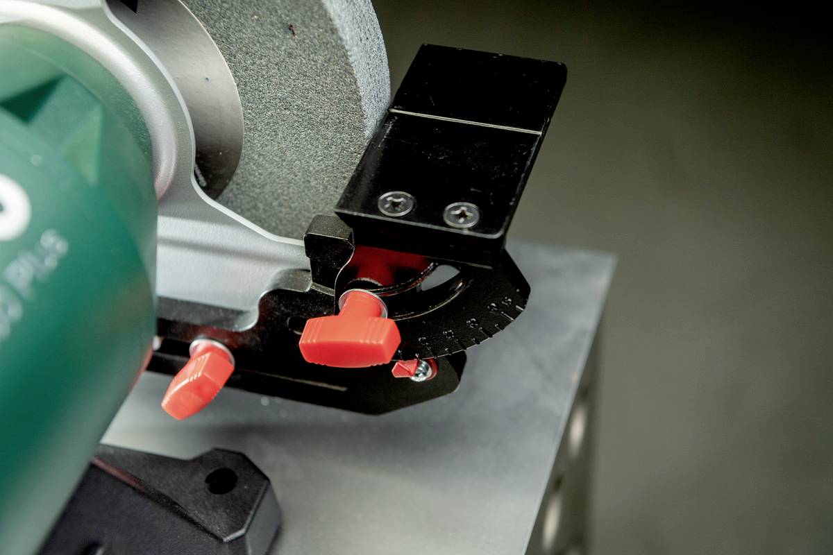 A grinding machine with a red adjustment knob. The machine is standing on a grey table and is ready for material processing.