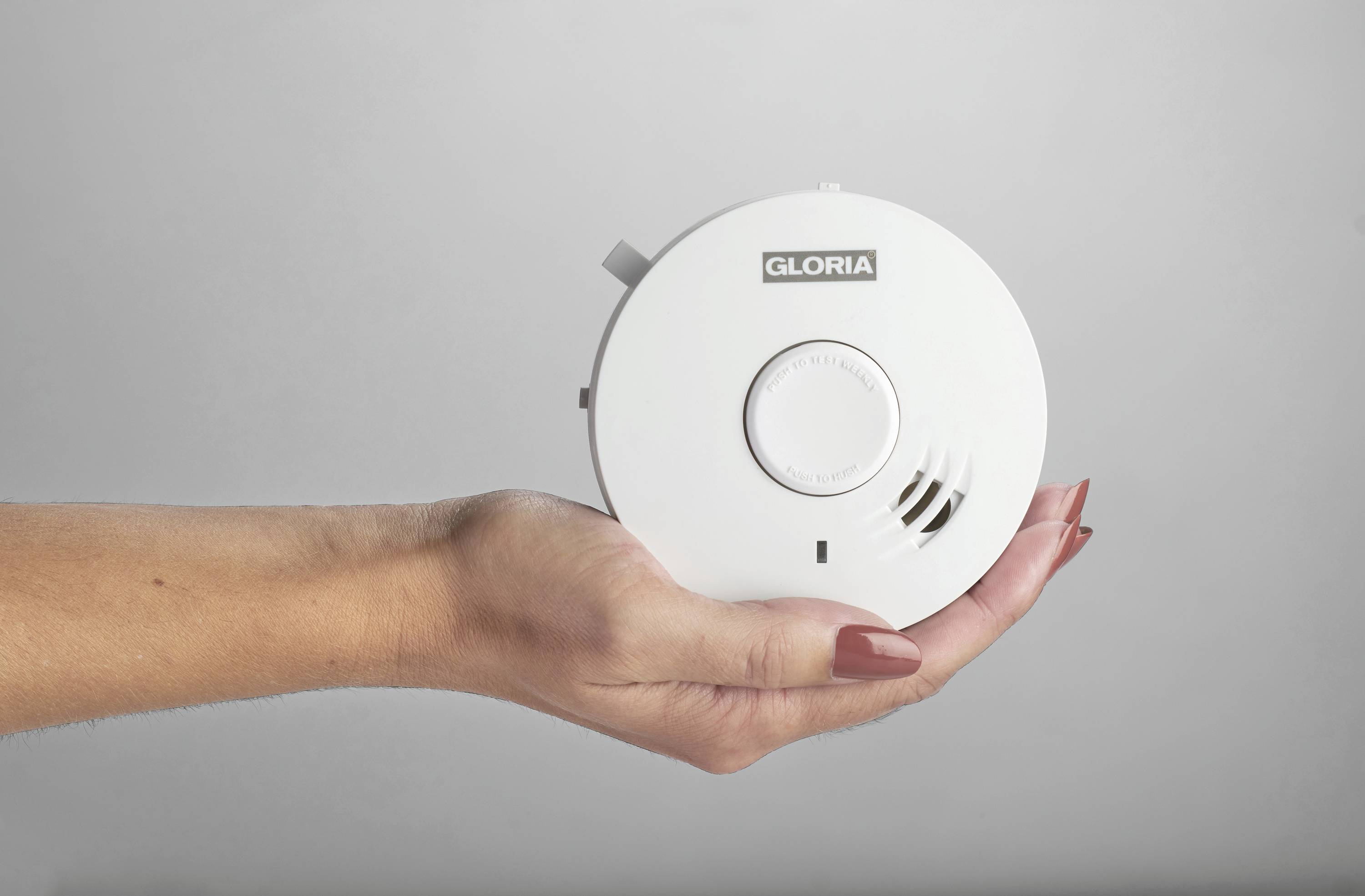 A hand is holding a smoke detector.