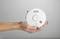 A hand is holding a smoke detector.