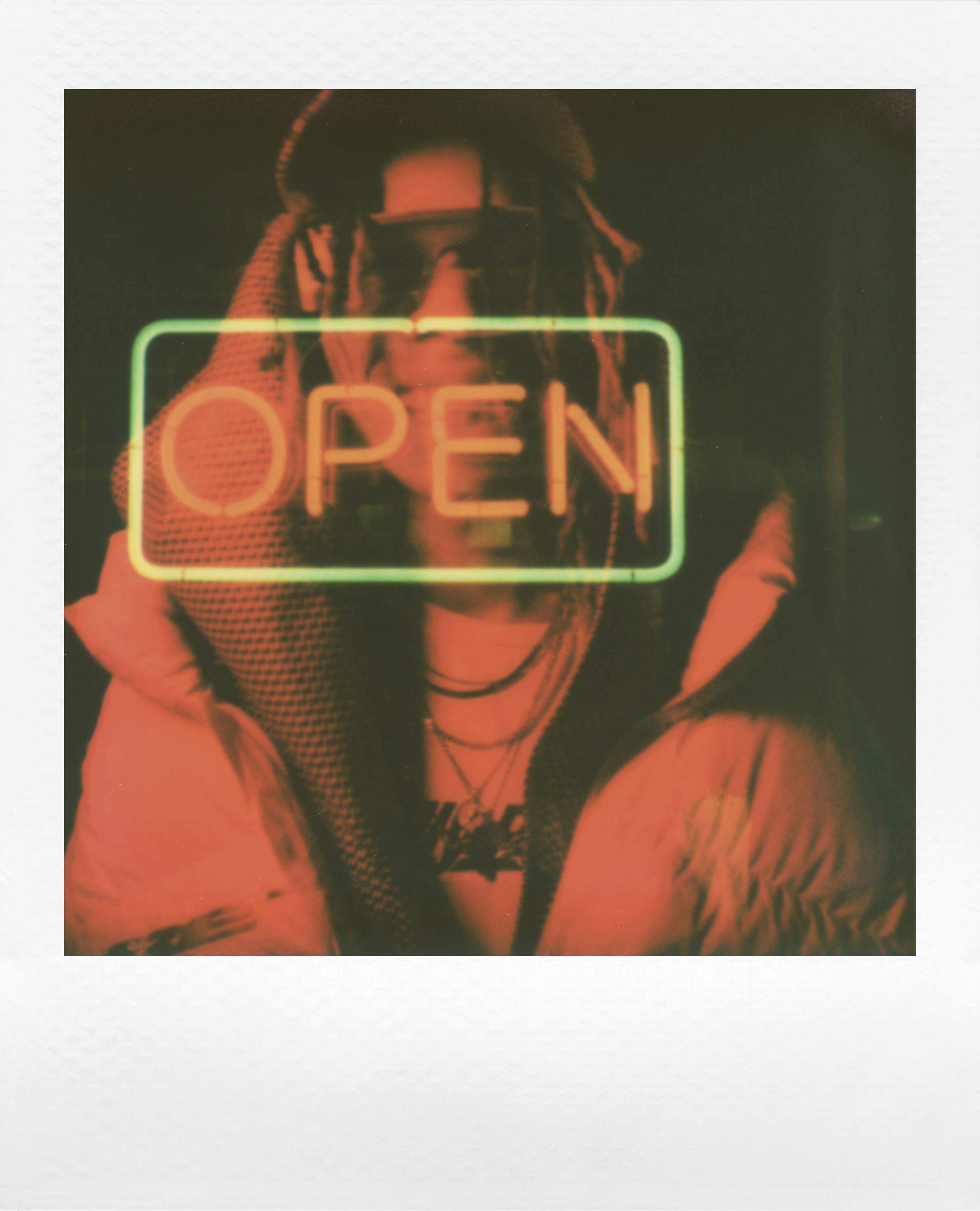 A person in a red-lit room is partially obscured by a glowing 'OPEN' sign.