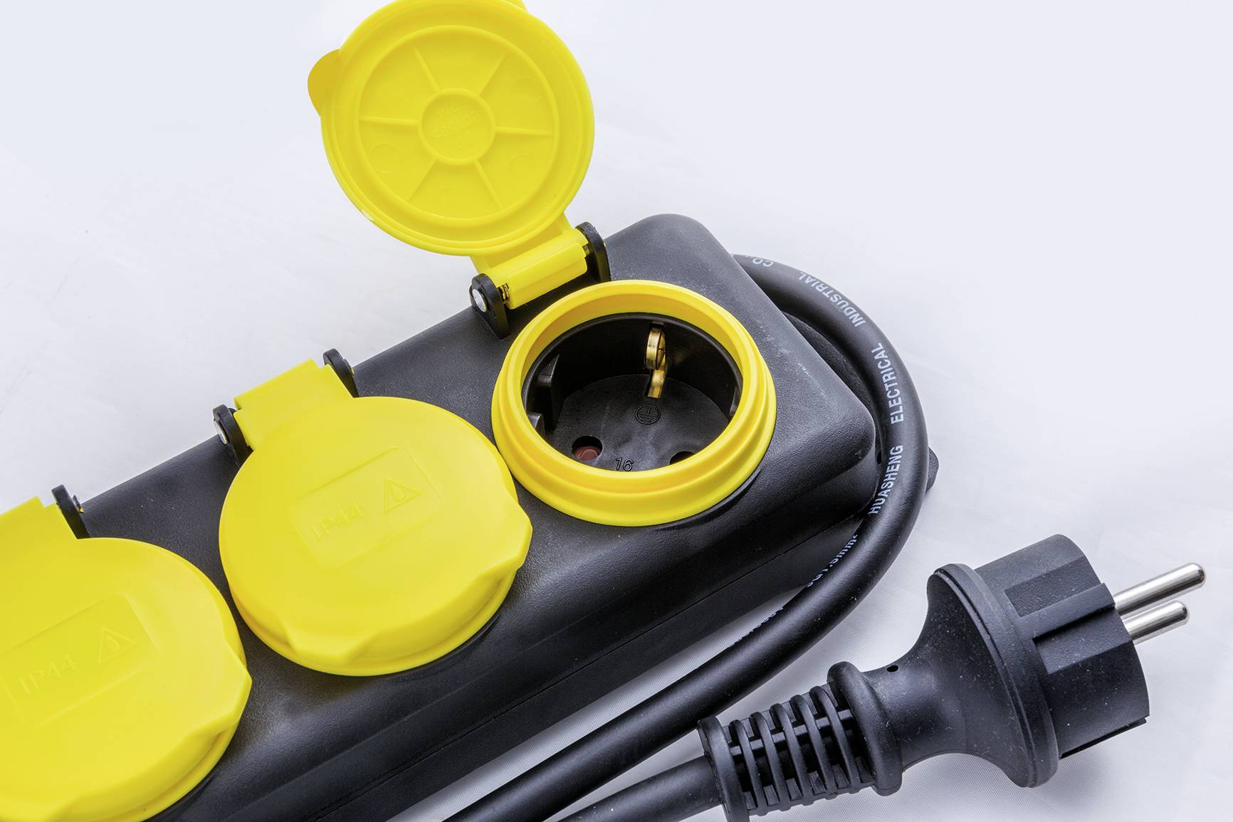 A three-socket extension lead with yellow flip-top covers and an attached black power cable on a white background.