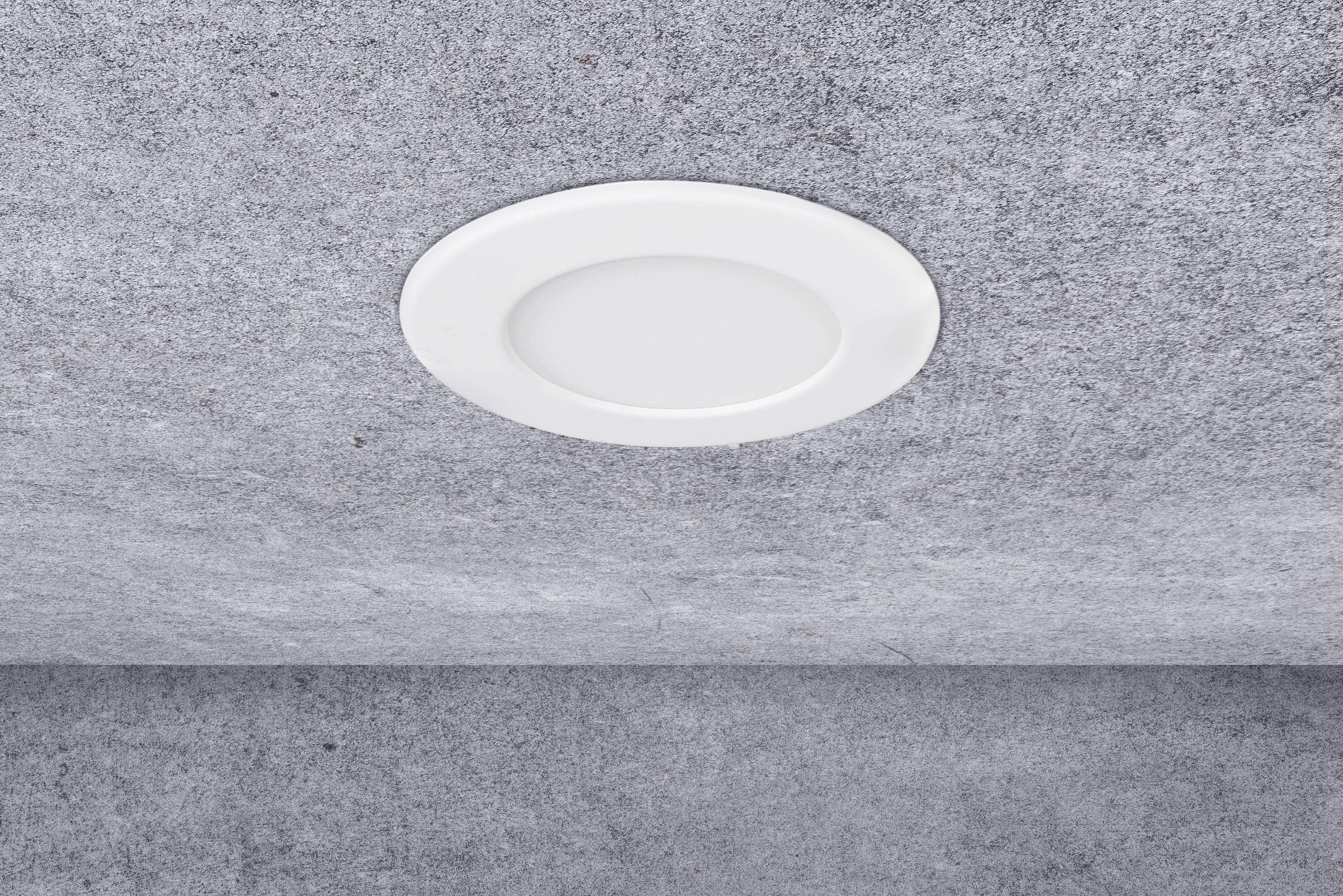 A round, white ceiling light is recessed into a grey ceiling.