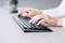 A person is typing on a modern, flat keyboard on a desk.