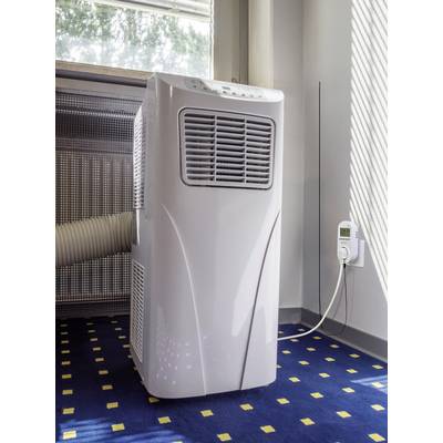 A portable air conditioning unit stands in a room with blue carpet. A hose is connected to the device and leads to a window.