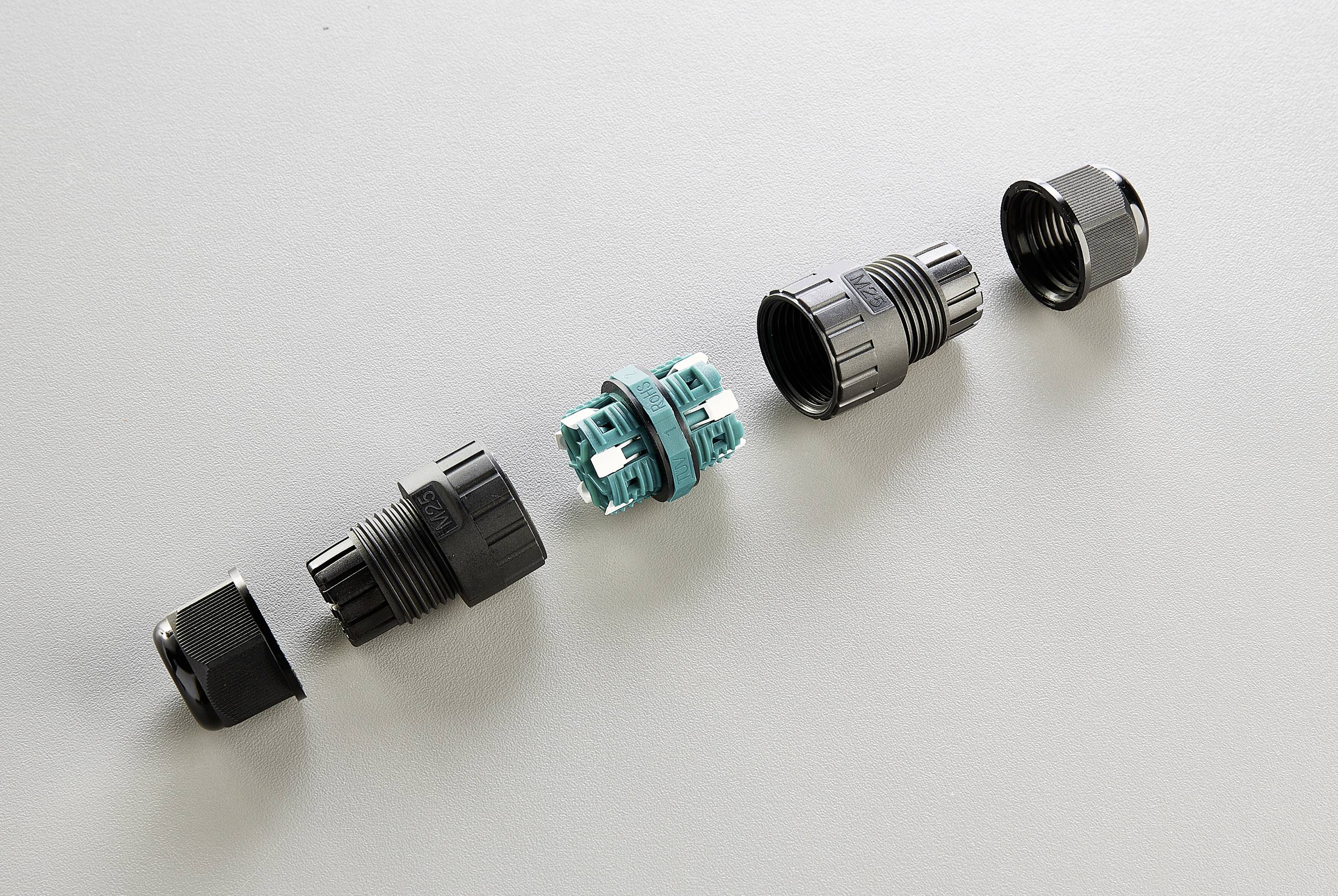 A disassembled electrical connector on a grey background shows several components in a row, including housing and terminals.