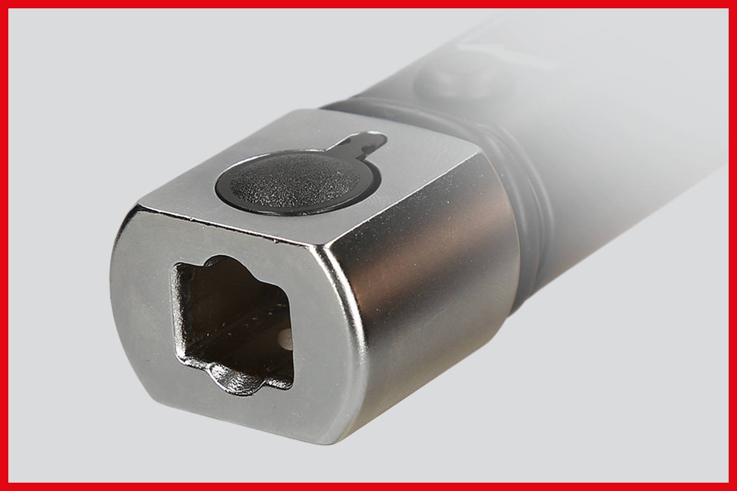 Close-up of a metallic tool with a rectangular cutout, possibly a socket wrench insert, against a grey background.