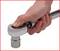 A hand is operating a torque wrench with a chrome-plated handle. The thumb is pressing a button on the head of the tool.