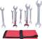 Eight silver spanners in various sizes stand upright behind a red tool roll.
