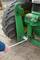 A person is using a spanner to repair a green agricultural machine.
