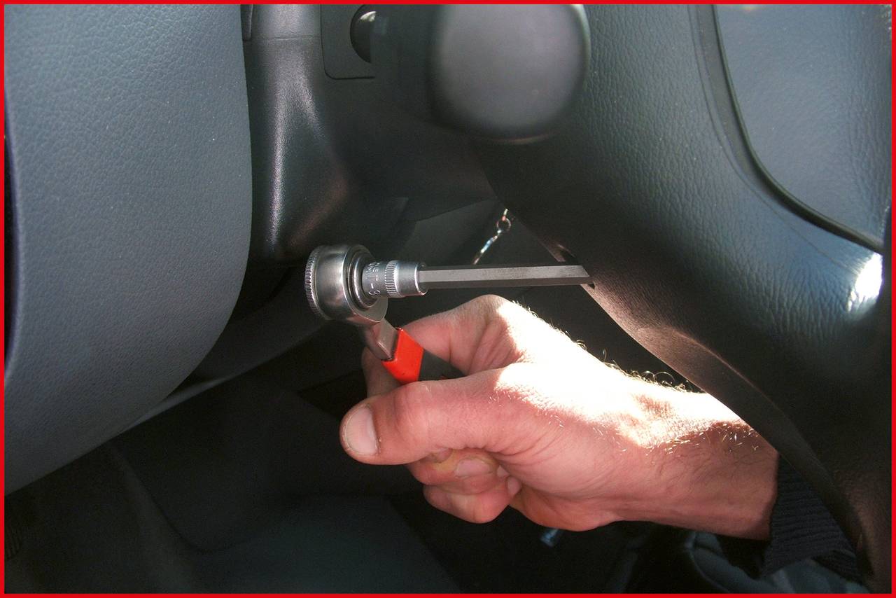 'Close-up of a hand holding a tool and working on an ignition switch in a car.'