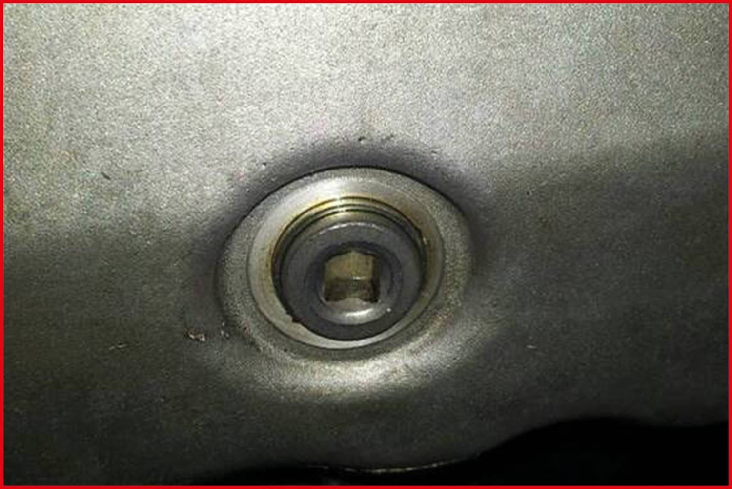 Close-up of a metal hole with a hexagonal screw aperture in a smooth surface.