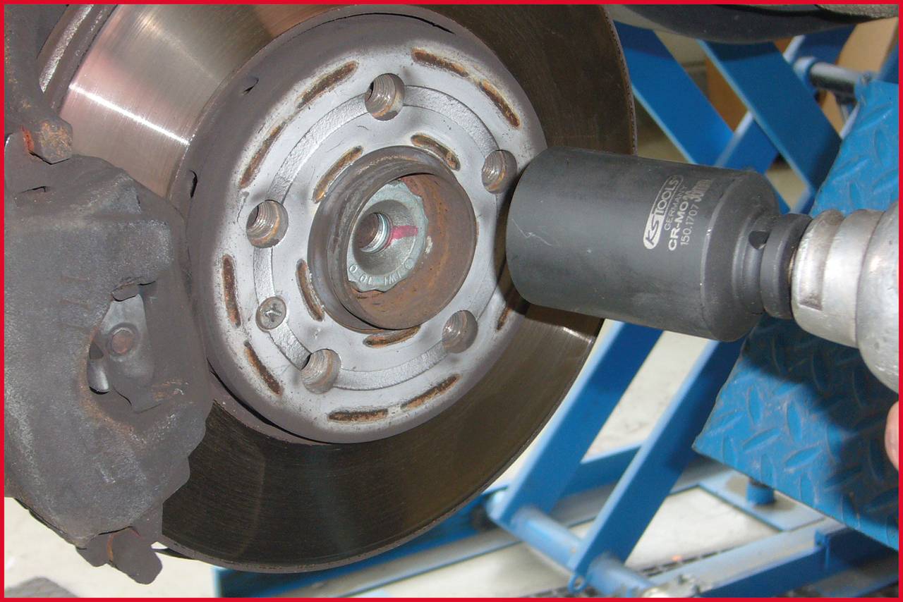 'Mechanic secures wheel nut with impact drill on car brake rotor.'