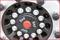 Close-up of a black tyre wheel with silver nuts and a red central button with 'SAF' written on it.