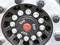 Close-up of a lorry wheel with multiple bolts around a central wheel hub cap. The hub cap has a red dot in the centre.