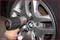 A hand is using an impact driver to loosen or tighten the wheel nut of a car with a BMW logo.