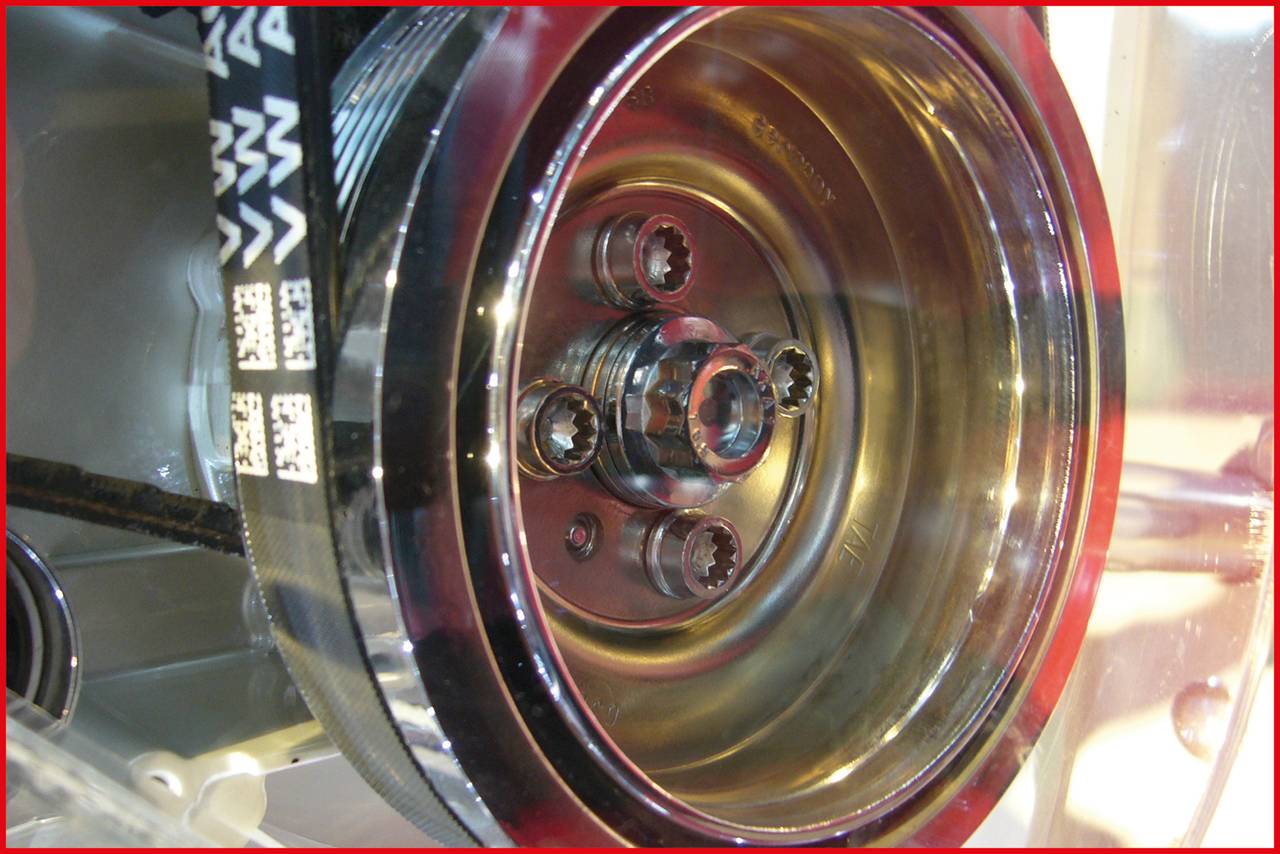 Close-up of a metal gear wheel with multiple screws in a mechanical device, revealing technical details and structures.