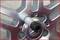 Close-up of a car wheel rim with silver spokes. A spanner is positioned in the centre, ready for disassembly.