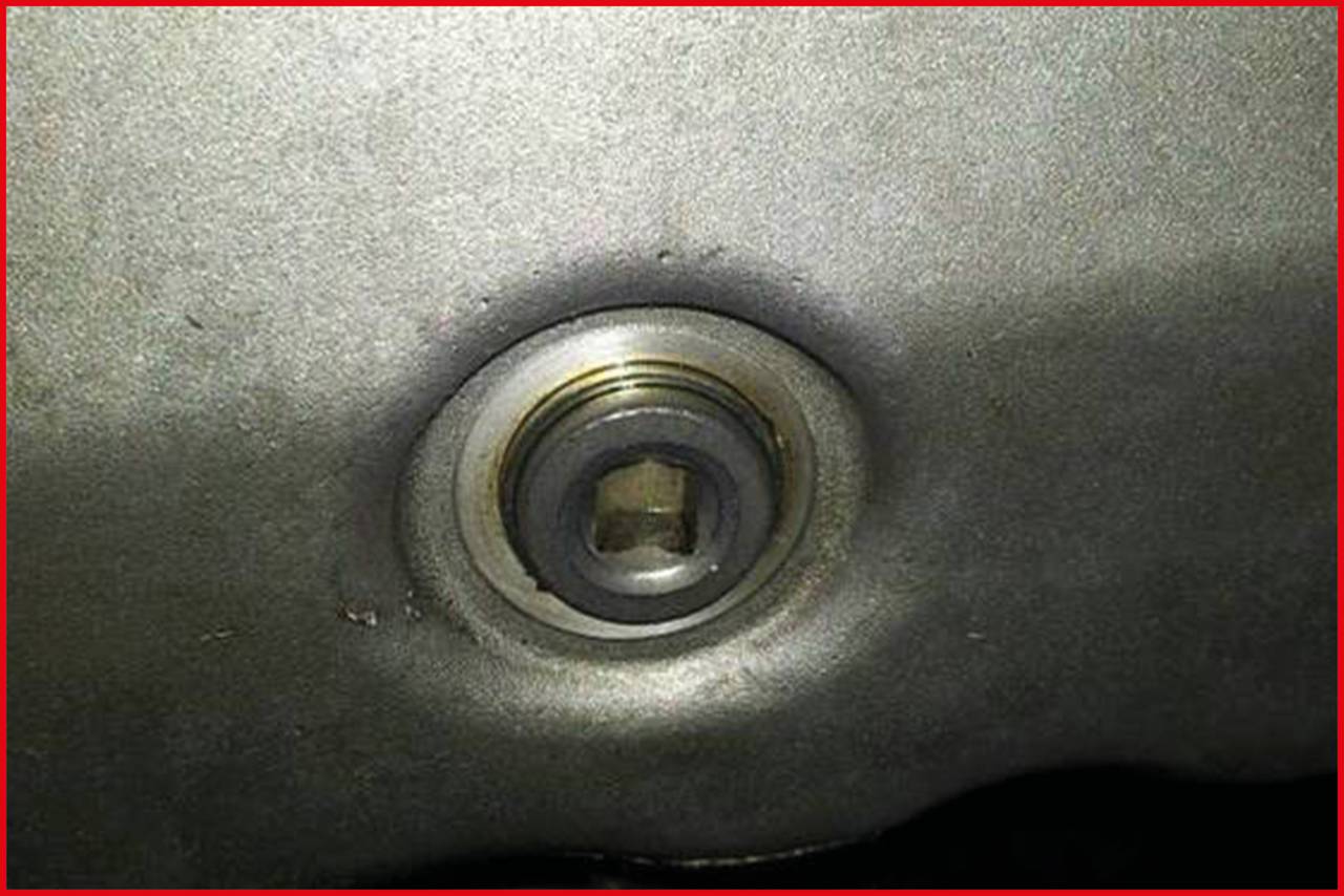 Close-up of a metal surface with a recessed screw or bolt opening in the centre.