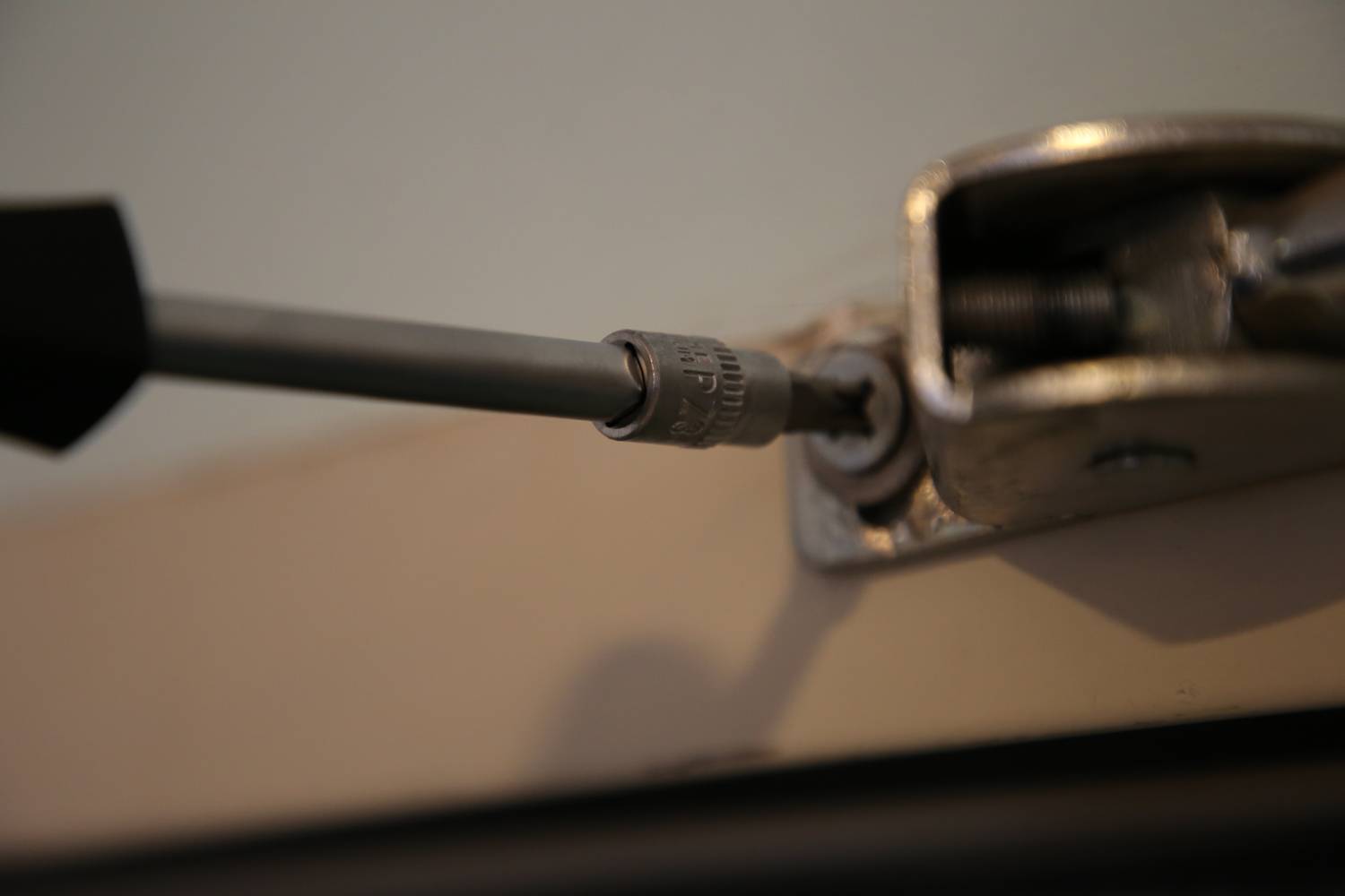 Close-up of a screwdriver tightening a screw in a metal fitting.