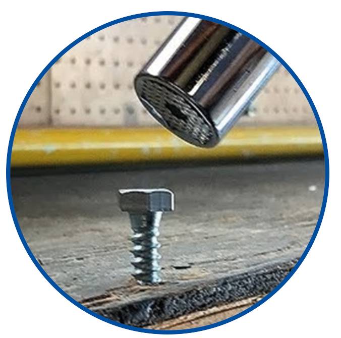 A hammer hovers over a screw that is screwed into a wooden surface.