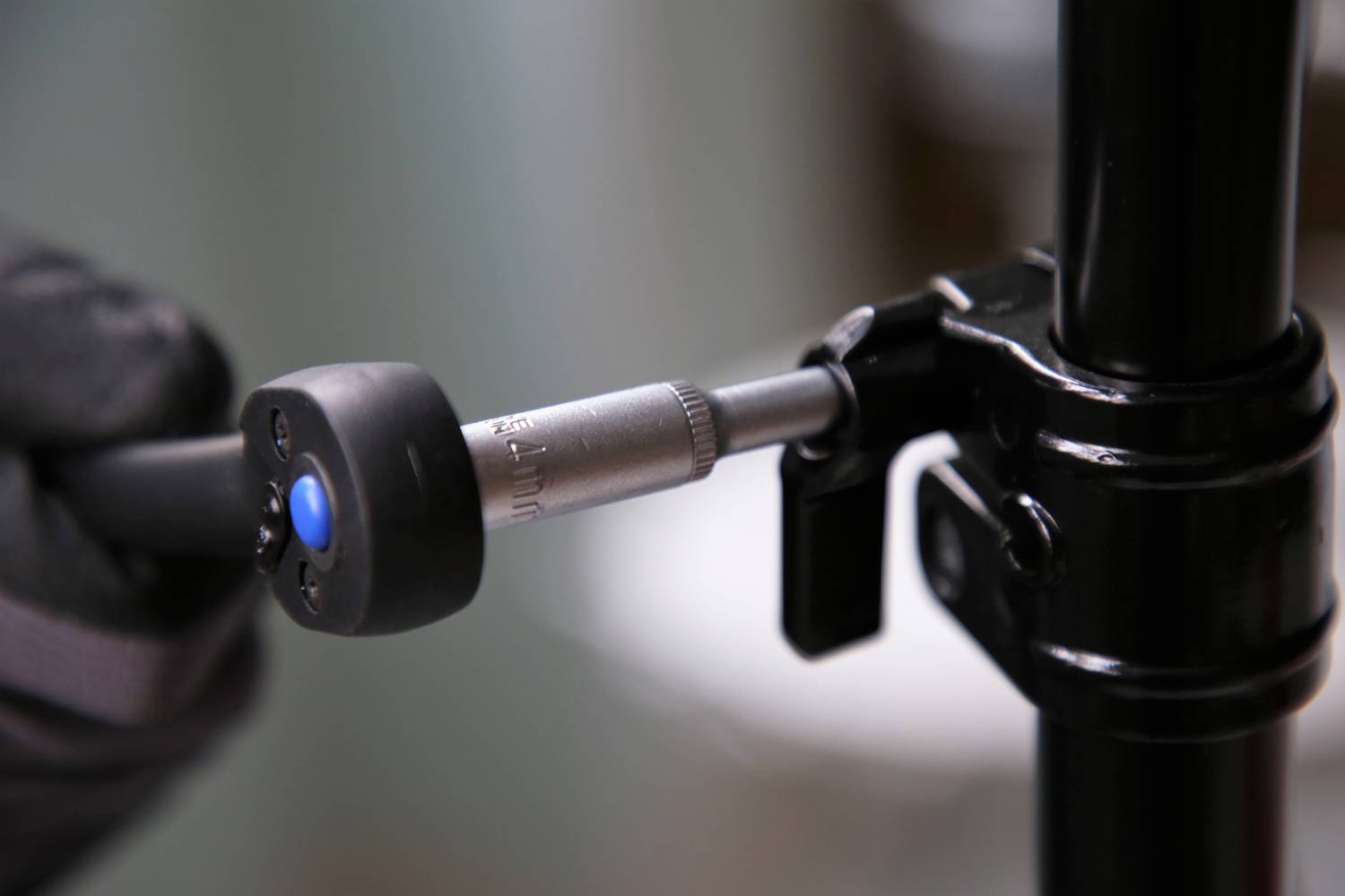 'Close-up of a hand using an Allen key to tighten a screw and secure a black stand/tripod. Focus on the tool and screw.'